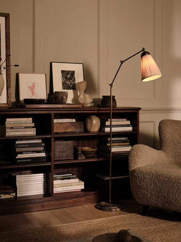 Nest living room with a bookshelf, floor lamp, and armchair.