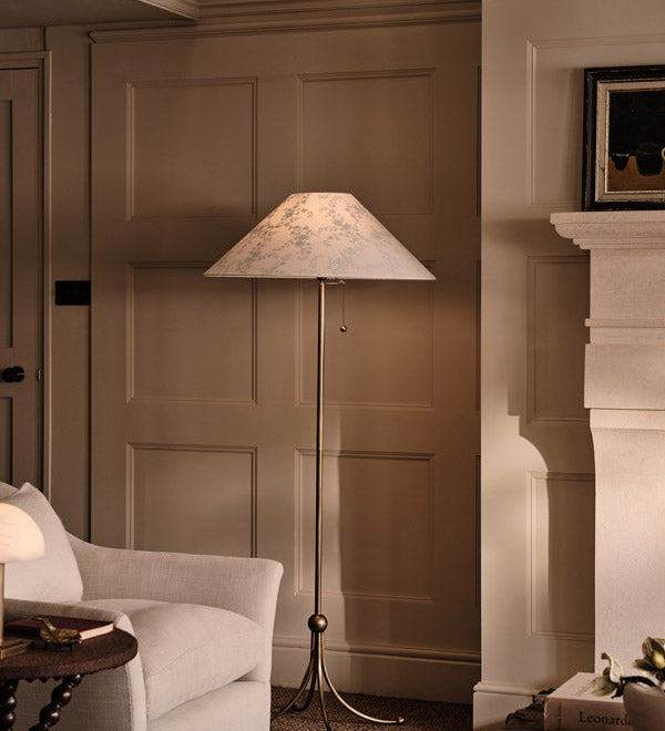 Floor lamp in a room with panelled walls and a fireplace.