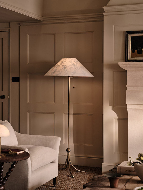 Floor lamp in a room with panelled walls and a fireplace.