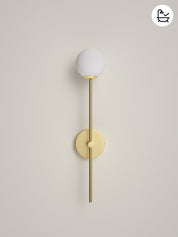 Wall-mounted light fixture with white globe and gold arm on a beige background