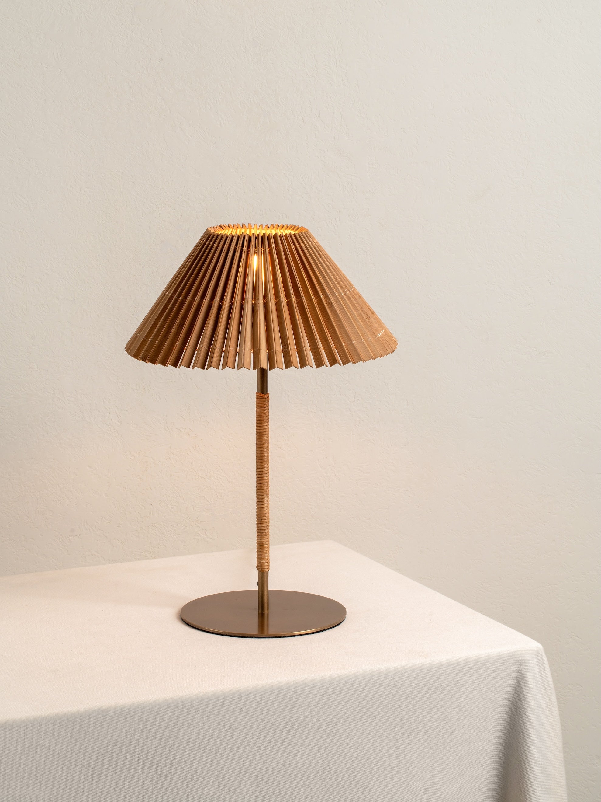 Table lamp with pleated brown shade on a white surface against a beige wall