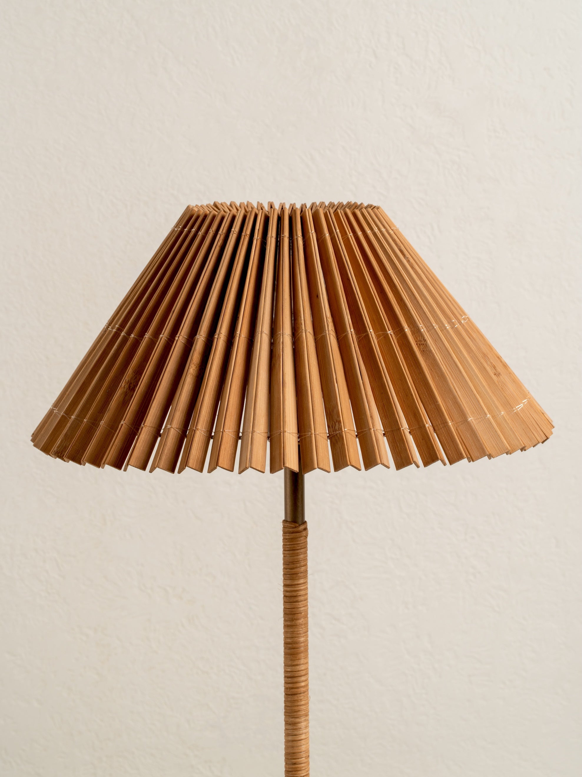 Floor lamp with a pleated brown lampshade on a beige background
