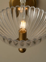 Close-up of a chandelier with a scalloped glass shade and gold fixture.