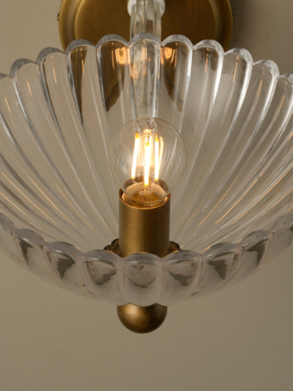 Close-up of a chandelier with a scalloped glass shade and gold fixture.