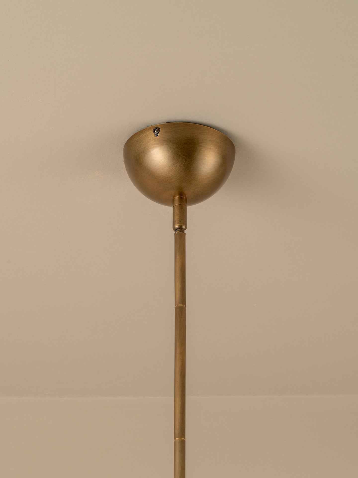 Brass pendant light fixture on a beige ceiling
