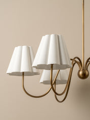 Chandelier with white lampshades and gold fixture on a beige background