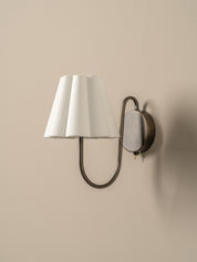 Wall-mounted lamp with a white shade and bronze fixture on a beige wall.