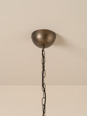 A dome-shaped ceiling mount with a dark bronze finish and a matching dark metal chain, shown against a plain beige wall and ceiling.