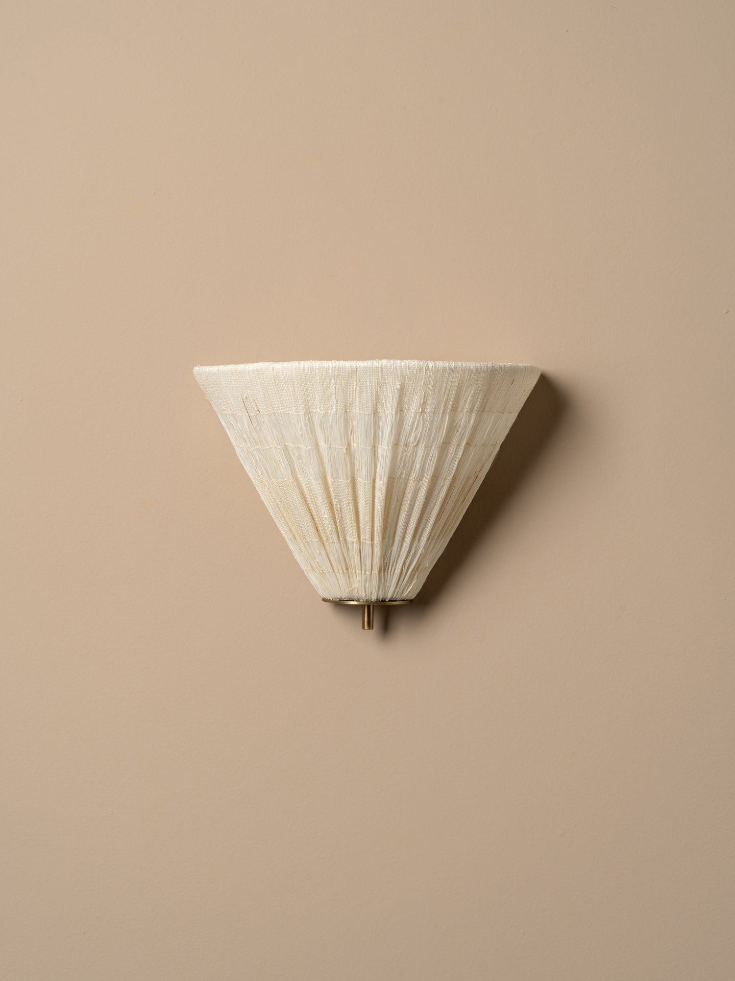 A modern wall sconce with a pleated, cone-shaped shade in a warm off-white or cream color, mounted on a solid beige wall.