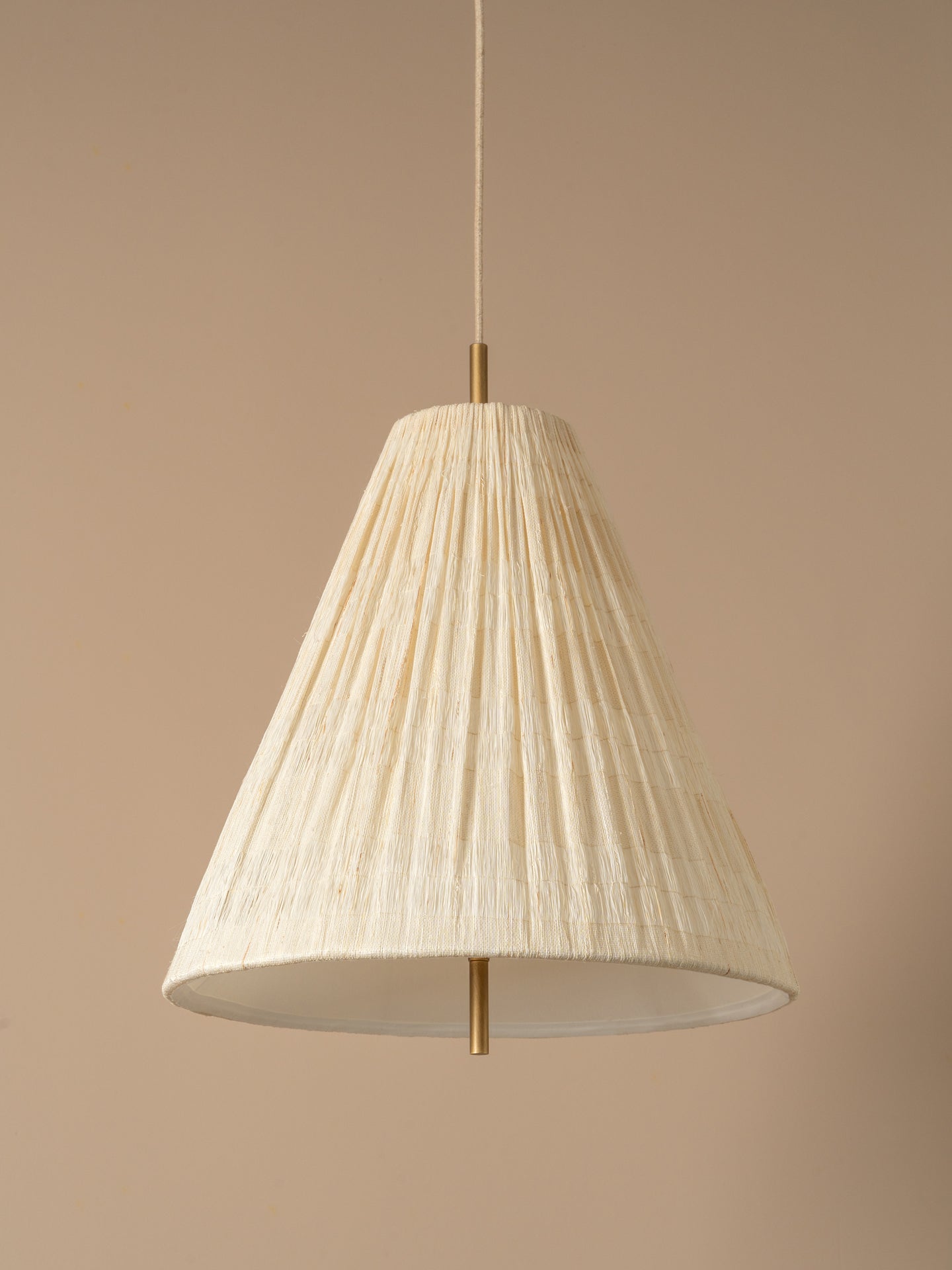  A conical pendant light shade made of textured, pleated cream-colored paper or fabric, suspended by a thin cord against a solid warm beige background.