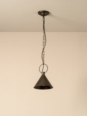 A single hanging pendant light with a dark bronze metal shade and chain, suspended from a ceiling against a plain beige wall.