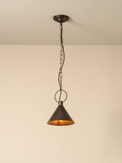 A single pendant light with a dark bronze metal shade and chain, hanging against a plain beige wall and ceiling.