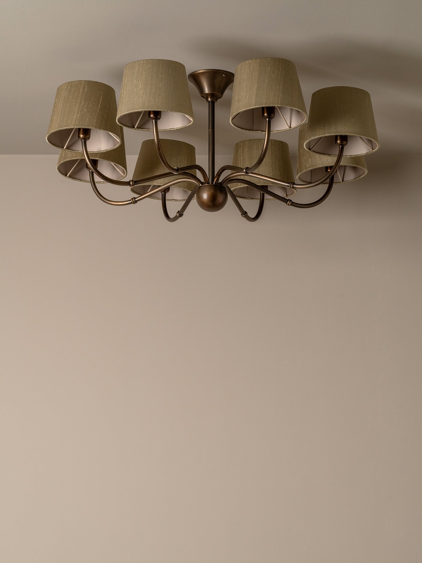 A six-light ceiling fixture with drum shades, shown mounted on a plain beige wall and ceiling.