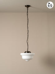 Vintage-style pendant light with white glass shade and black metal chain against a beige wall.