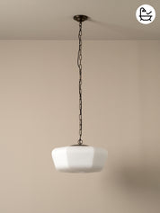 White pendant light hanging from a chain against a beige wall.