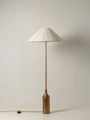 Floor lamp with a pleated white shade on a plain background