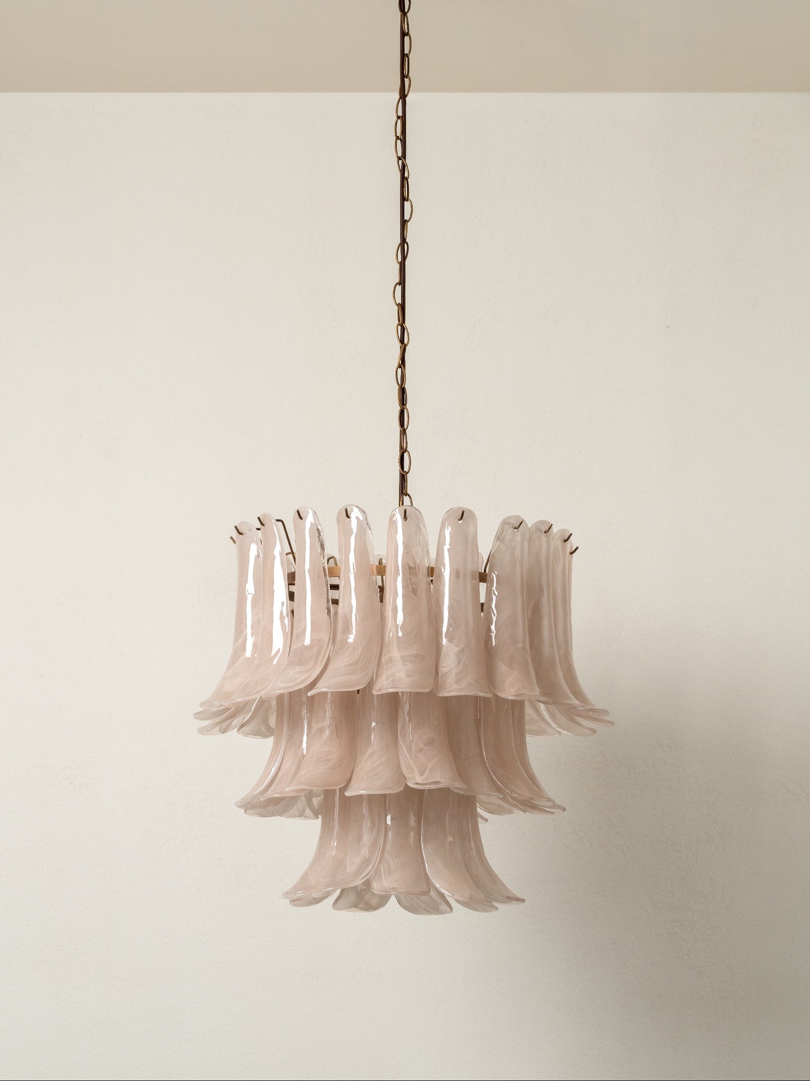 Pink chandelier hanging against a plain wall