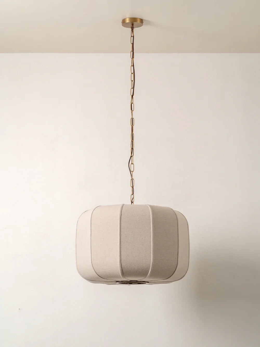 Beige pendant light hanging against a plain white wall