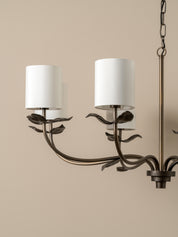 A close-up of a dark metal ceiling canopy and hanging chain fixture against a plain off-white wall.