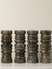 Set of five cylindrical marble stools with a textured surface on a light background