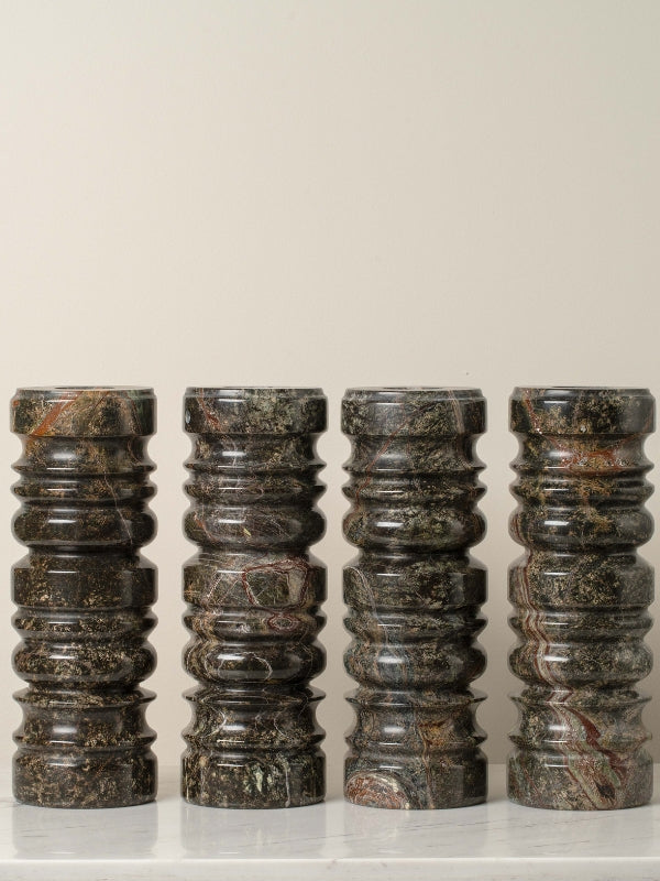Set of five cylindrical marble stools with a textured surface on a light background