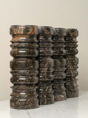 Stack of dark marble cylindrical objects on a light surface with a neutral background