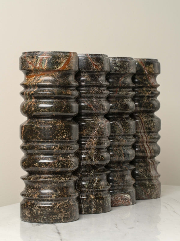 Stack of dark marble cylindrical objects on a light surface with a neutral background