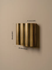 A wall-mounted cylindrical light fixture in a brushed brass finish, shown against a neutral beige wall with dimension labels indicating 25.2 cm width, 22 cm height, and 9.